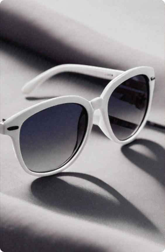 A pair of elegant sunglasses featuring a white frame with black accents resting on a soft surface.