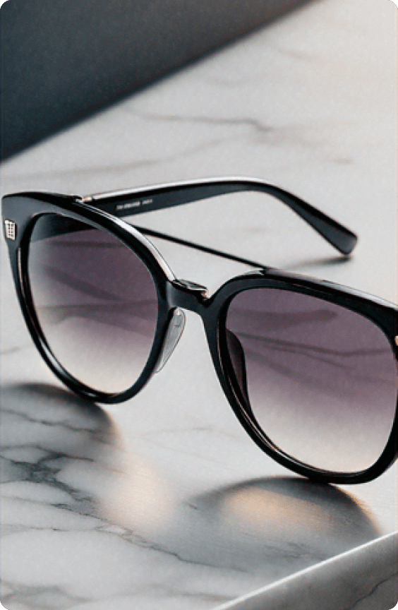 A stylish pair of sunglasses with black frames resting on a polished marble surface with soft lighting.